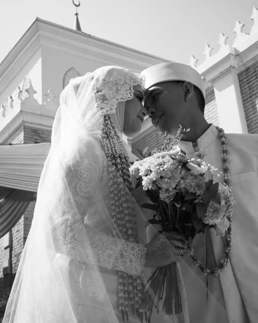 Potret hitam putih pasangan pengantin dalam busana pernikahan