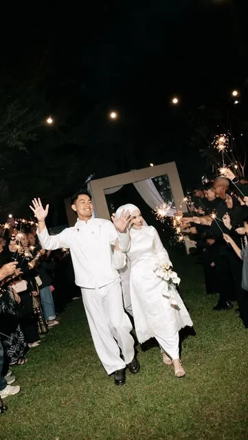 Pasangan pengantin berjalan di antara cahaya kembang api